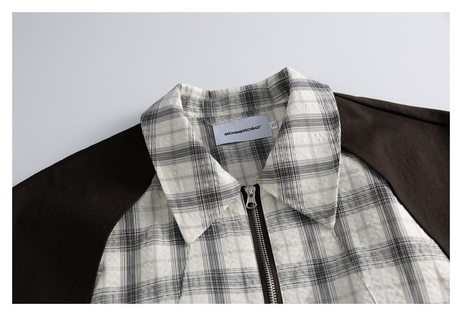 Framed close-up of the plaid jacket's wide collar, central zipper, and dark brown shoulder panels.