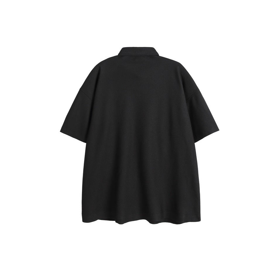 Back view of a plain black oversized short-sleeve collared shirt on a white background.