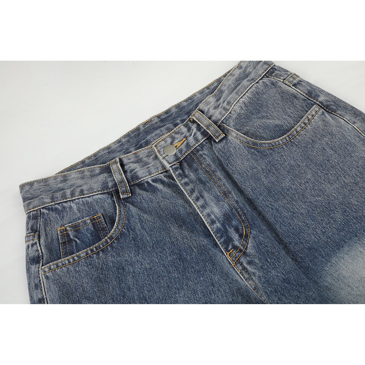 Close-up of blue acid-wash jeans showing the front waistband, button, belt loops, fly and pockets.