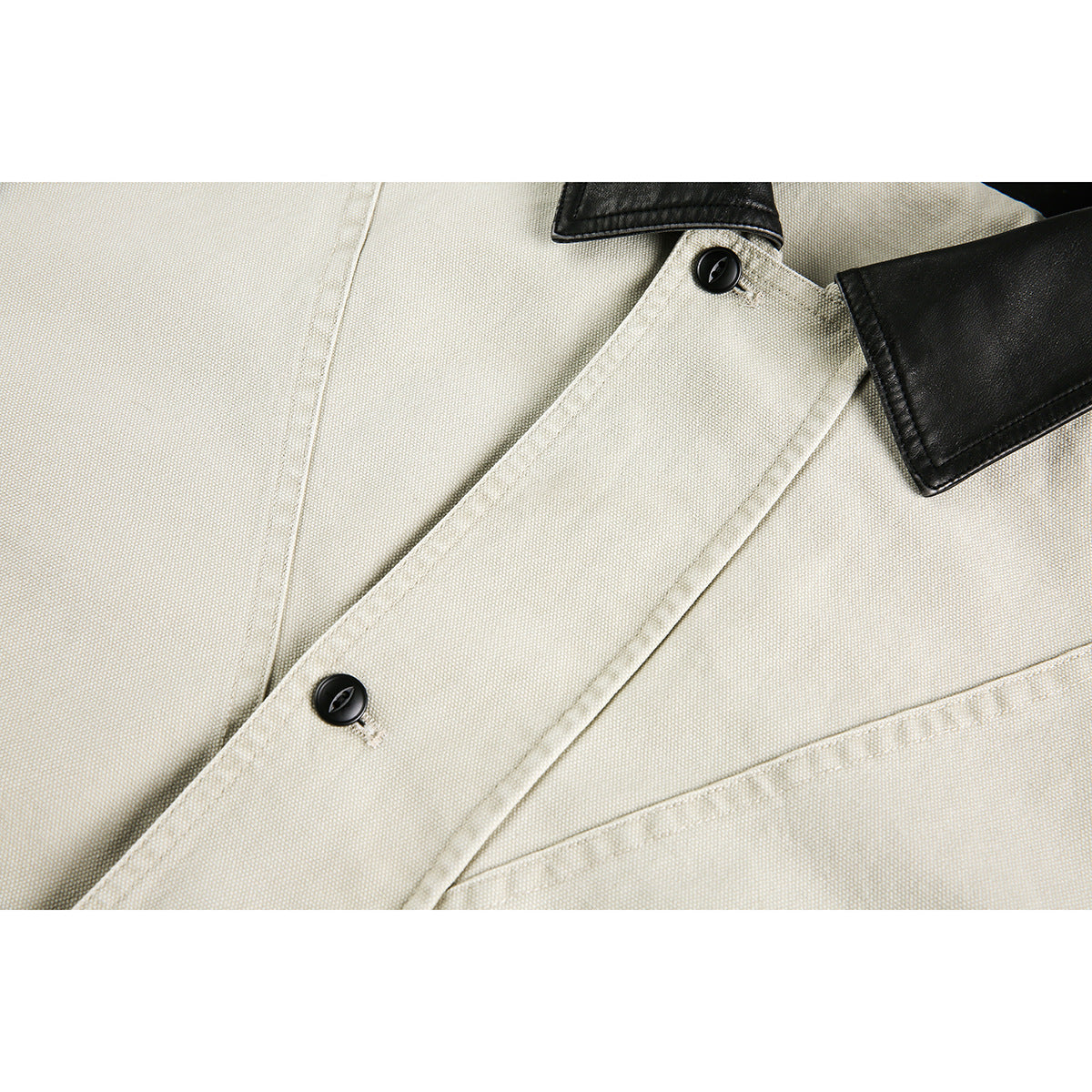 Close-up of a light beige jacket's front placket, black buttons, and black collar.