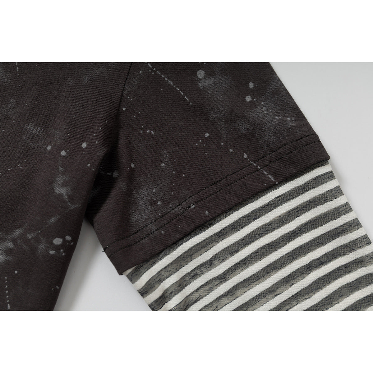 Close-up of a dark sleeve with a gray-and-off-white striped cuff and scattered pale markings.