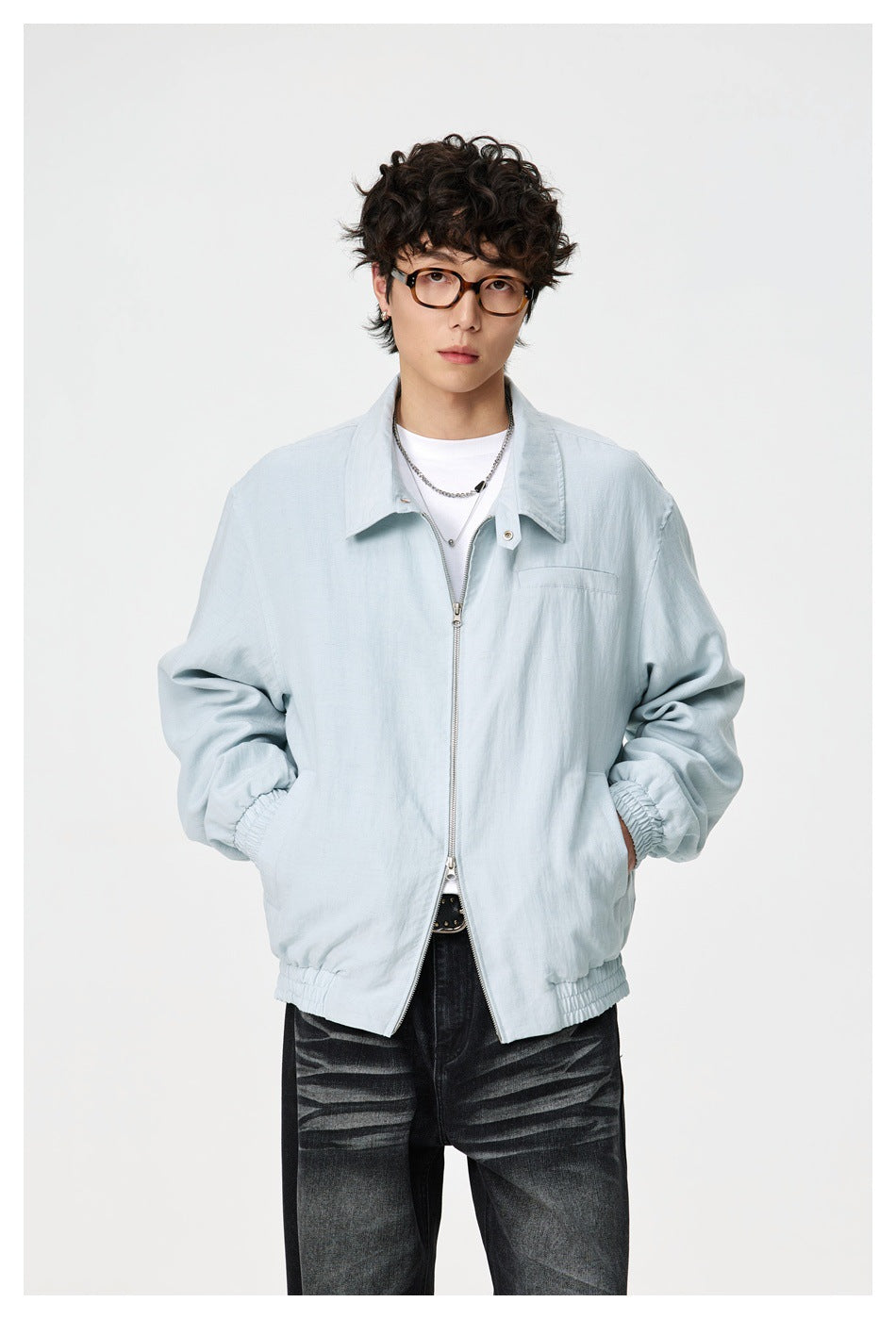 Model wearing a light blue zip-front collared jacket with elastic cuffs and hem over a white tee and dark jeans