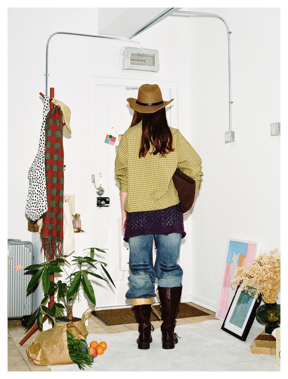Back view of a model wearing a yellow checked shirt, blue jeans, and a purple knit wrap.