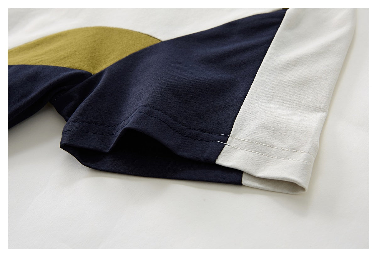 Close-up of a color-block shirt sleeve and hem in navy, ivory, and mustard.