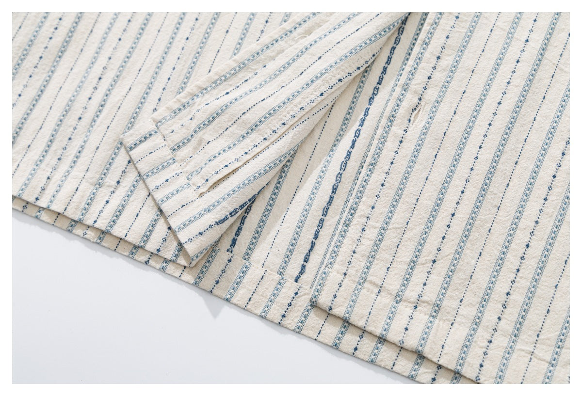 Close-up of off-white striped fabric showing a stitched hem and folded edge.