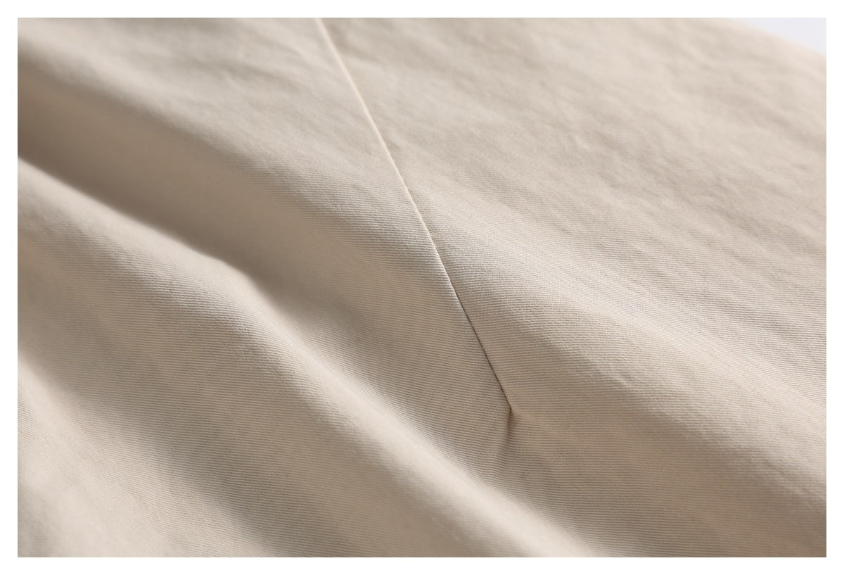 Extreme close-up of beige trouser fabric and a diagonal seam.