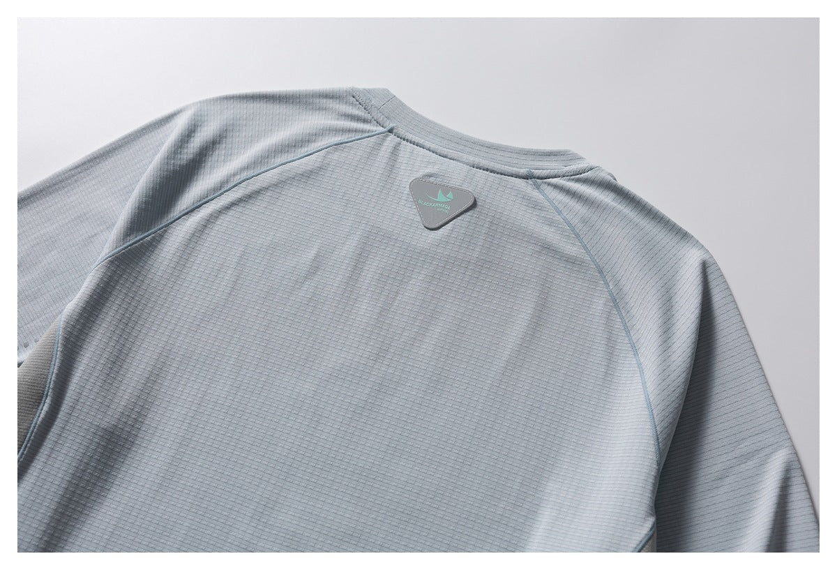 Close-up of a light gray textured shirt’s back neckline and shoulder seams, with a small triangular logo patch.