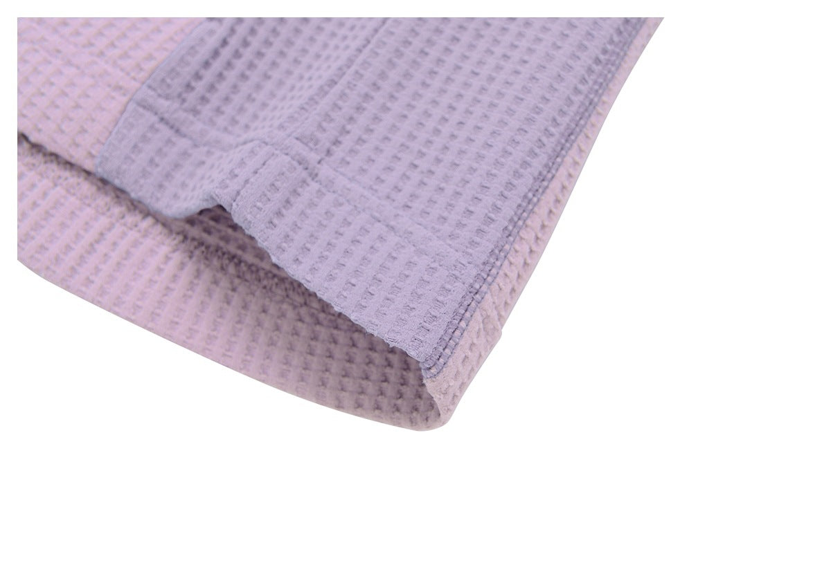 Close-up of pale lavender textured fabric folded at a stitched edge on a white background.