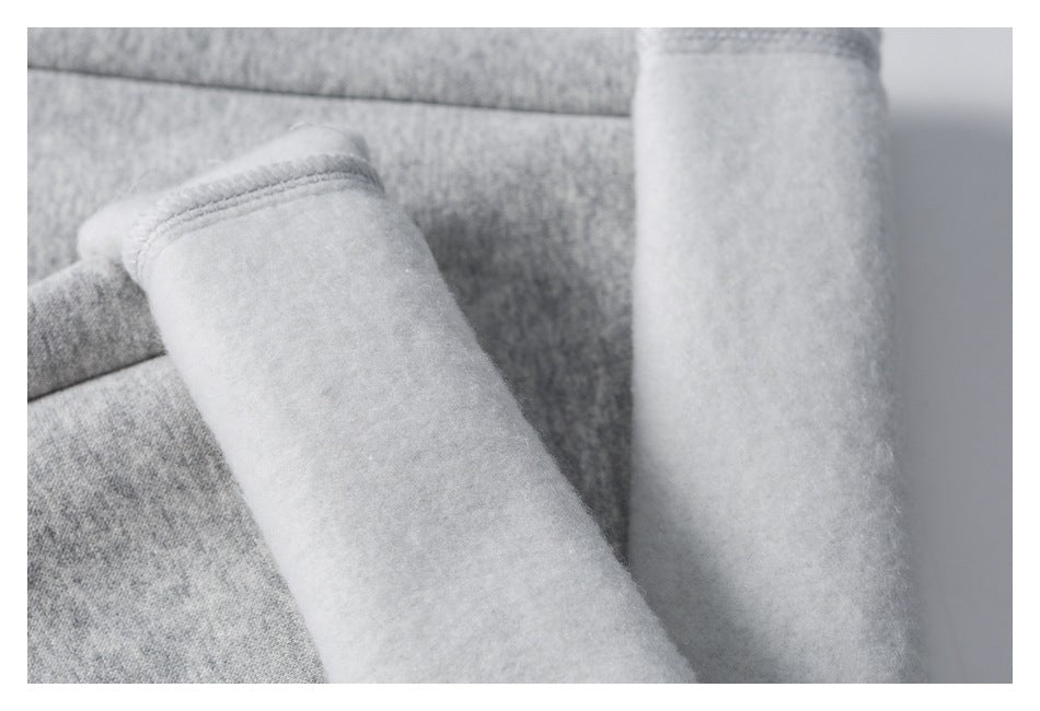 Close-up of a gray garment's soft white brushed interior and stitched seam.