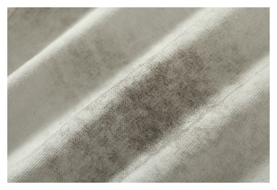 Close-up of softly folded off-white knit fabric showing its surface texture.