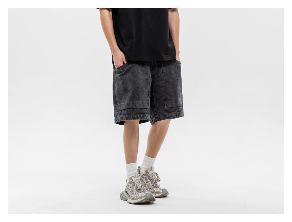 Person wearing black washed knee-length shorts with a black tee, white socks and sneakers, hands in pockets, cropped view