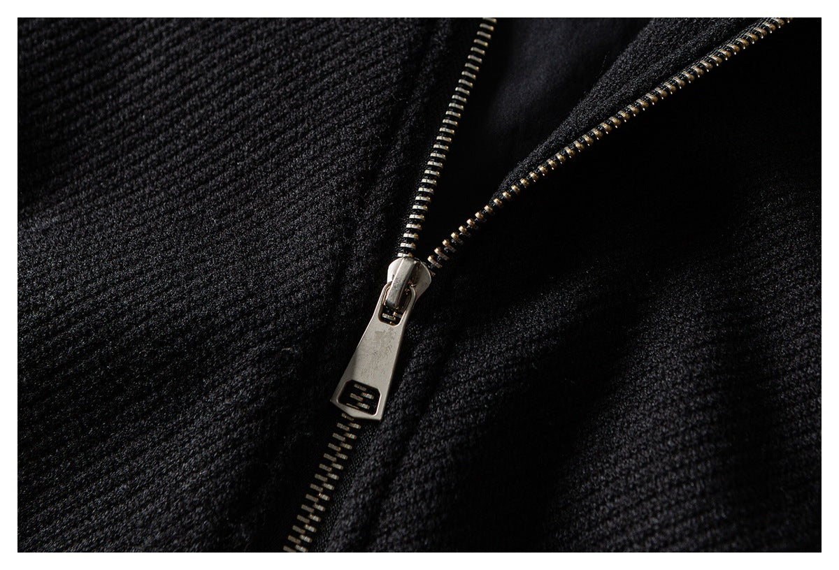 Close-up of a metal zipper and pull against textured black jacket fabric.