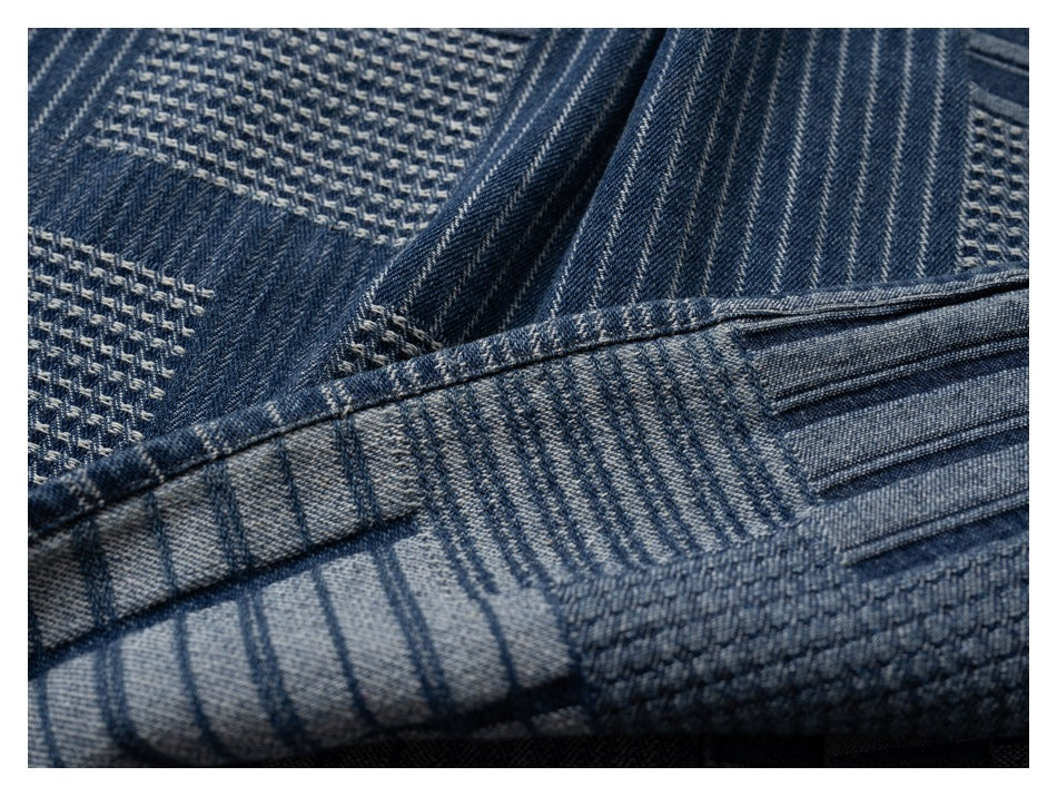 Close-up of the shirt hem and dark blue patchwork fabric with contrasting stripes and woven blocks.