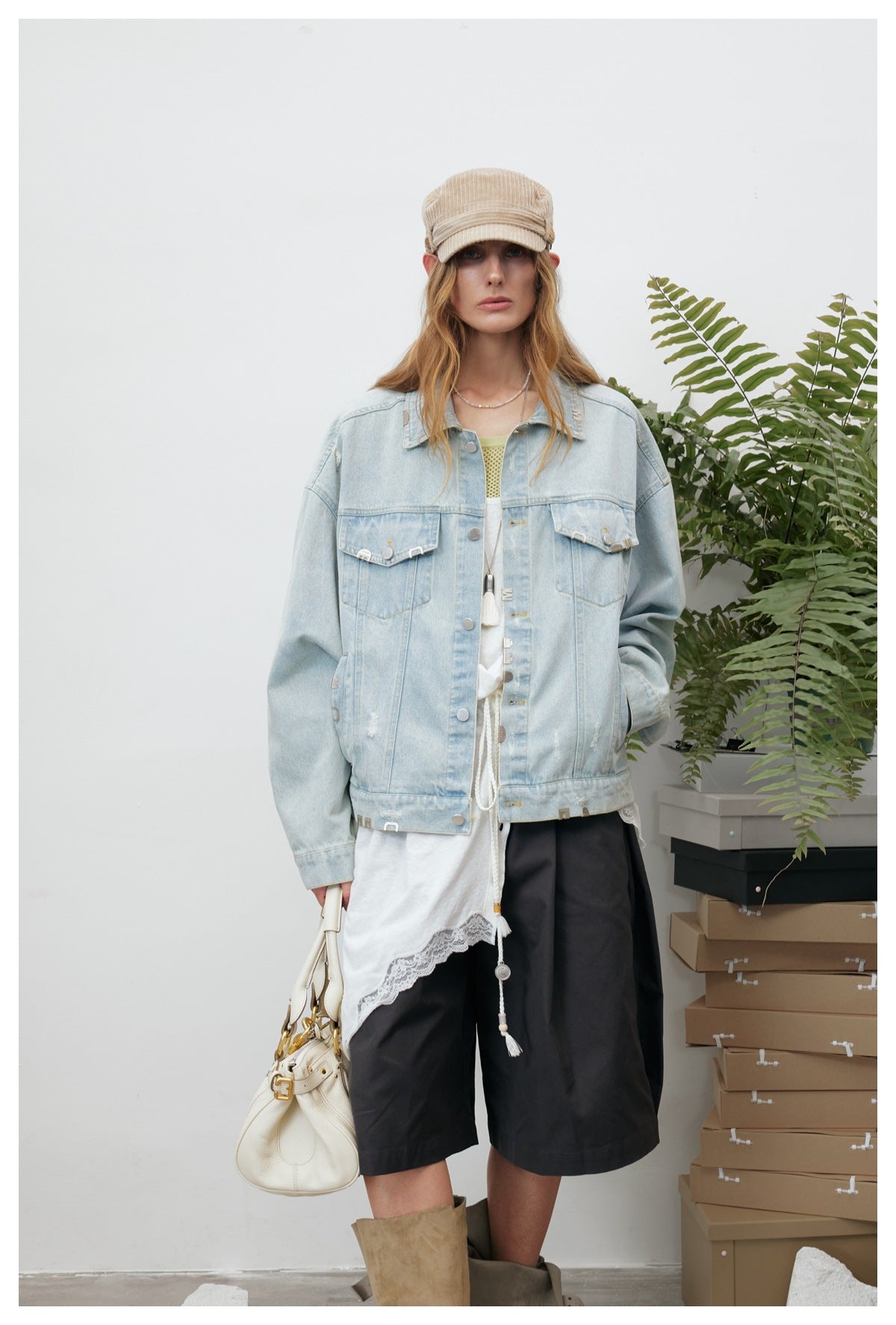 Front view of a model wearing an oversized light-wash denim jacket with black shorts and a white lace-trimmed top.