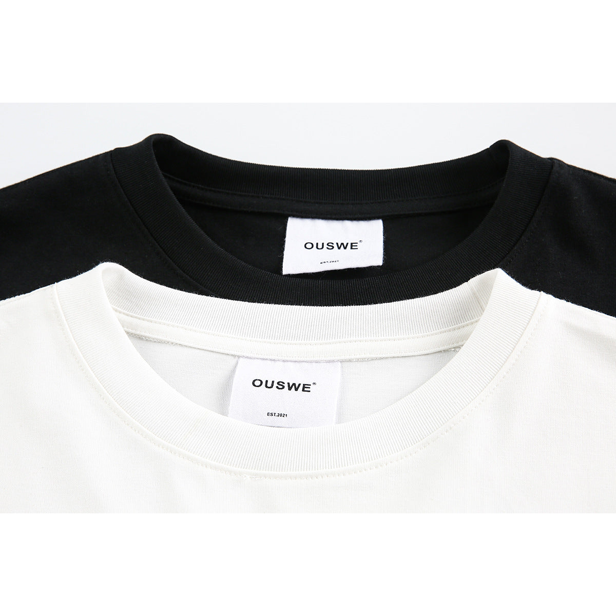Close-up of black and white T-shirt crew necks with OUSWE labels.