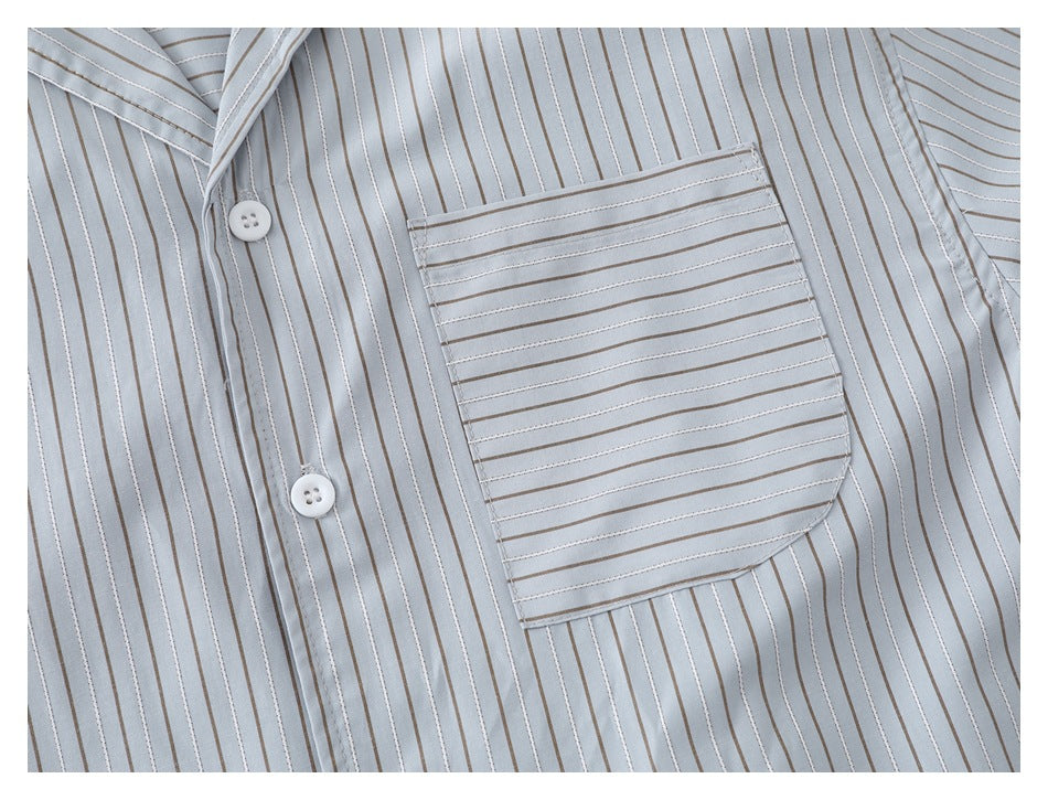 Close-up of a pale blue-gray striped shirt front, showing white buttons and a large chest pocket.