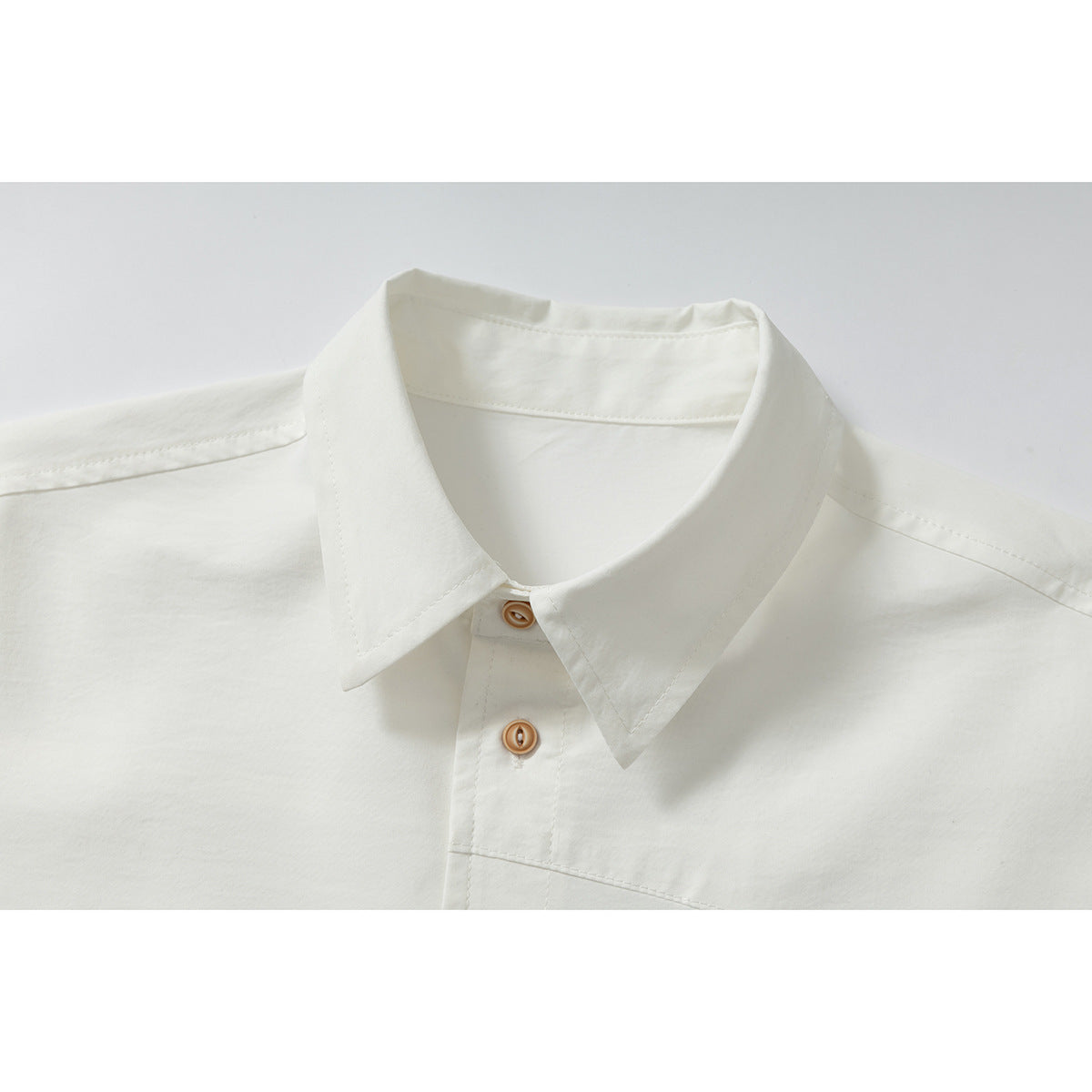 Close-up of an off-white shirt collar and upper placket with tan buttons.