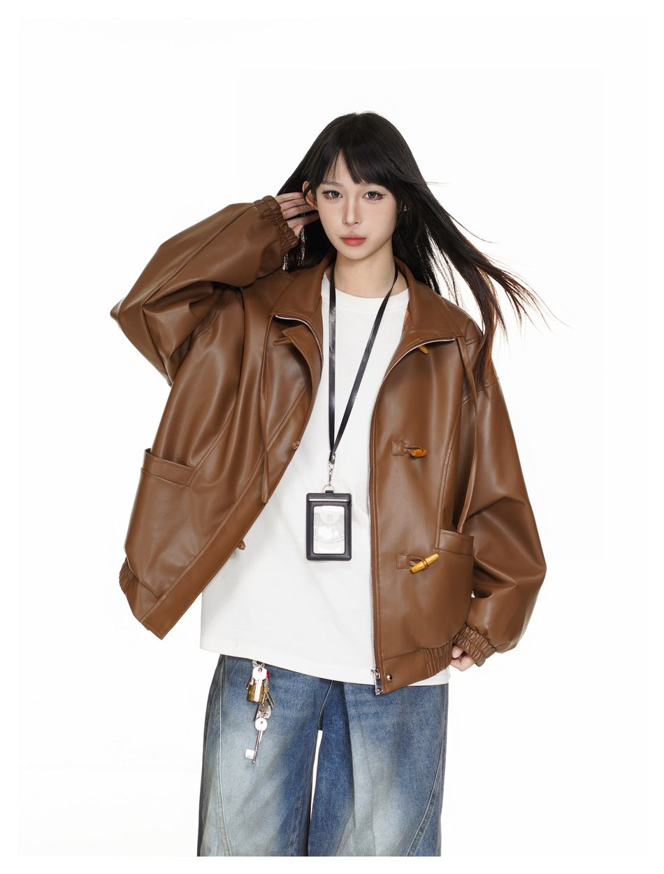 Closer view of a model wearing an open brown jacket with toggle details over a white shirt.