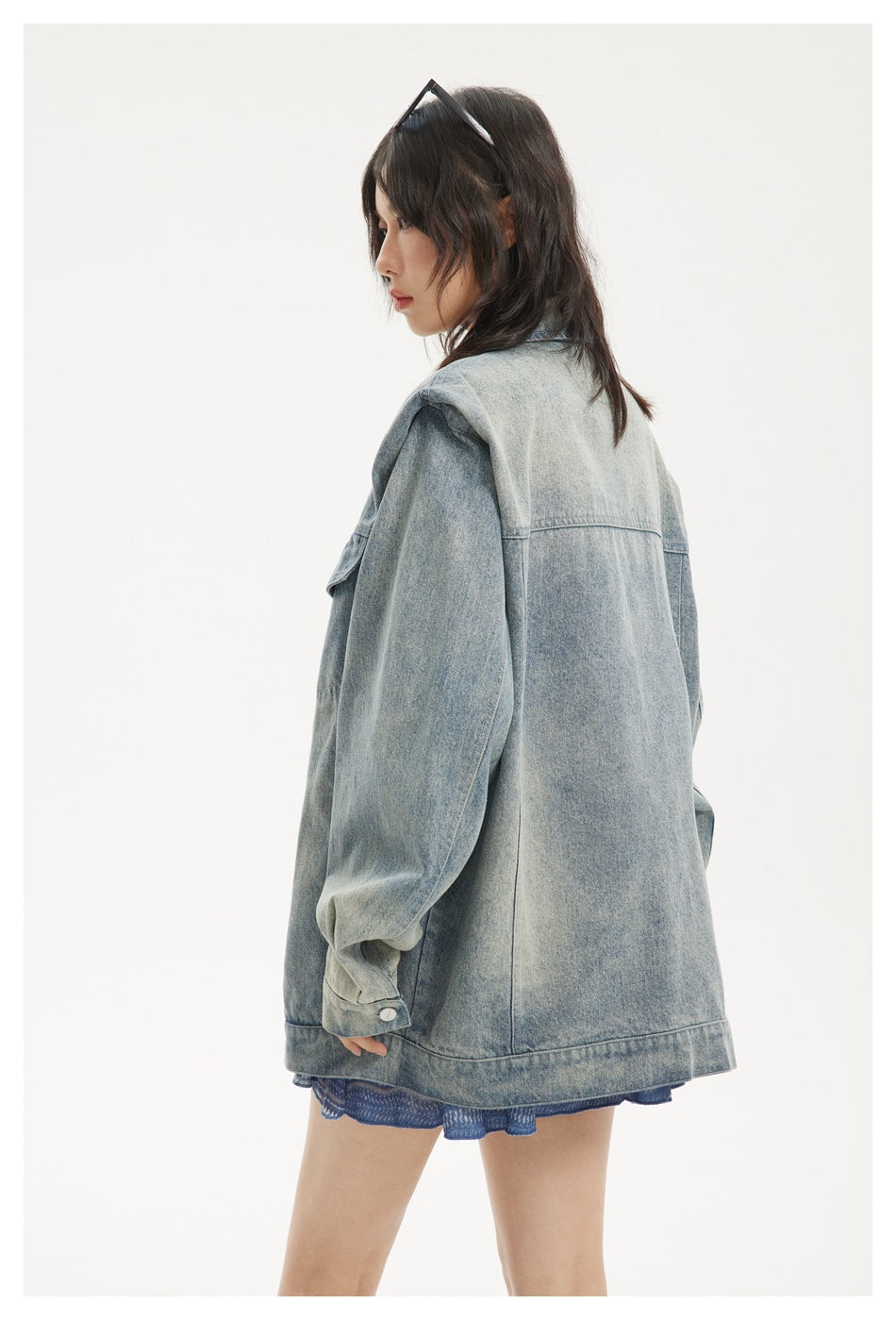 Side and rear view of a model wearing the oversized faded blue denim jacket, showing its roomy sleeve and back seams.
