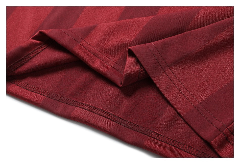 Close-up of the burgundy shirt's folded hem and stitched seams.