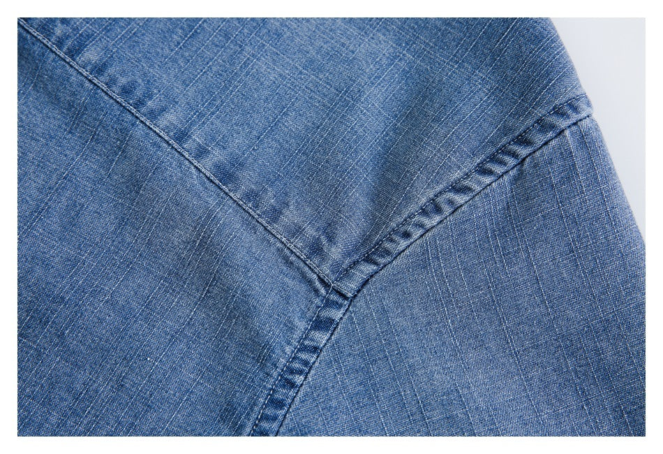 Close-up of blue denim with a curved, stitched seam joining fabric panels.