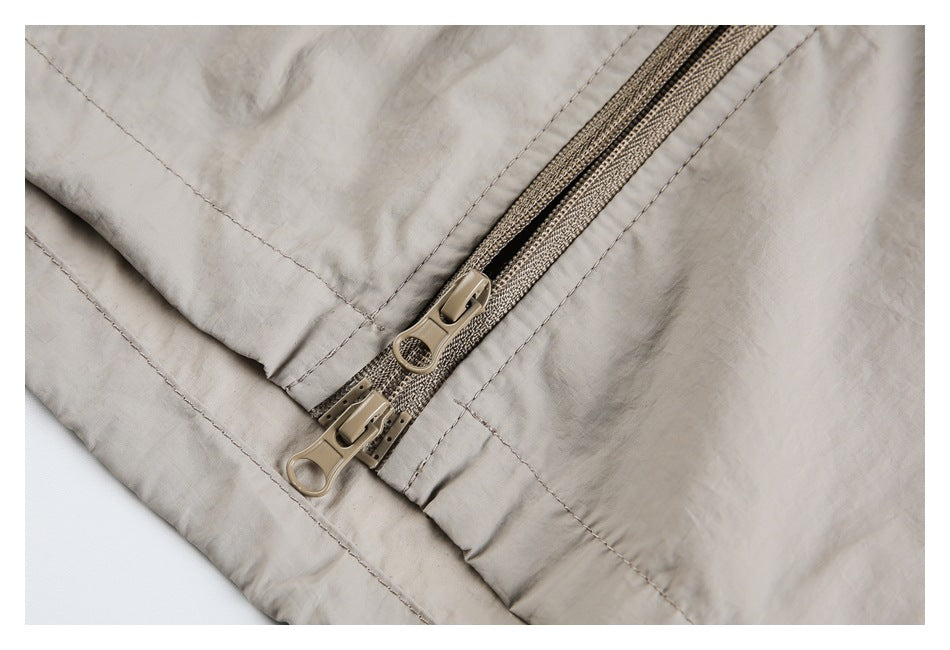 Close-up of two beige zipper pulls on the jacket's front zipper.
