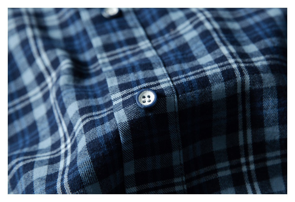 Close-up of blue and black plaid fabric with a light button on the placket.