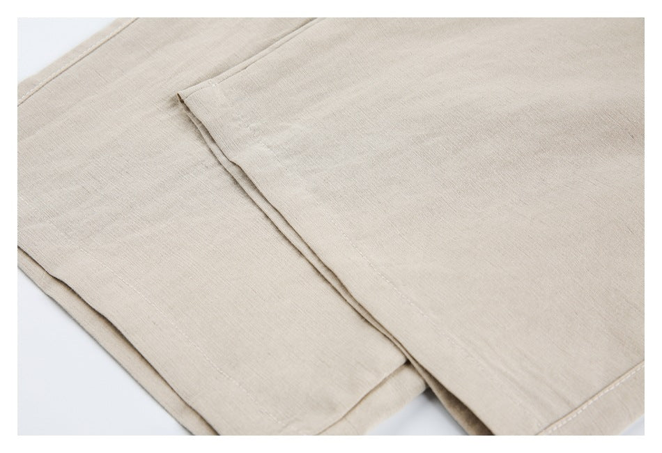 Close-up of overlapping beige trouser legs with stitched seams and finished hems.