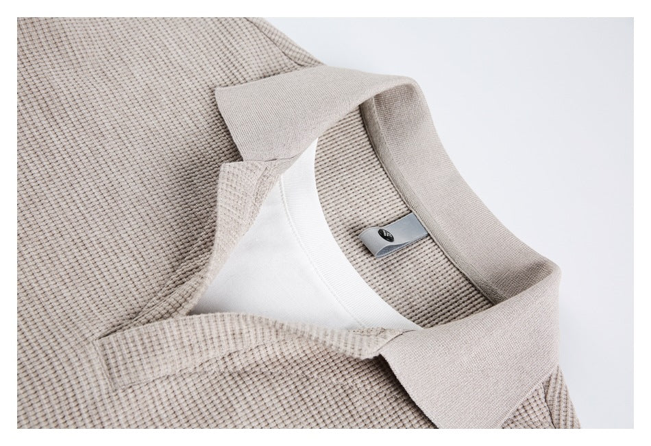 Close-up of a taupe shirt's textured fabric, collar, neckline, and small neck label.