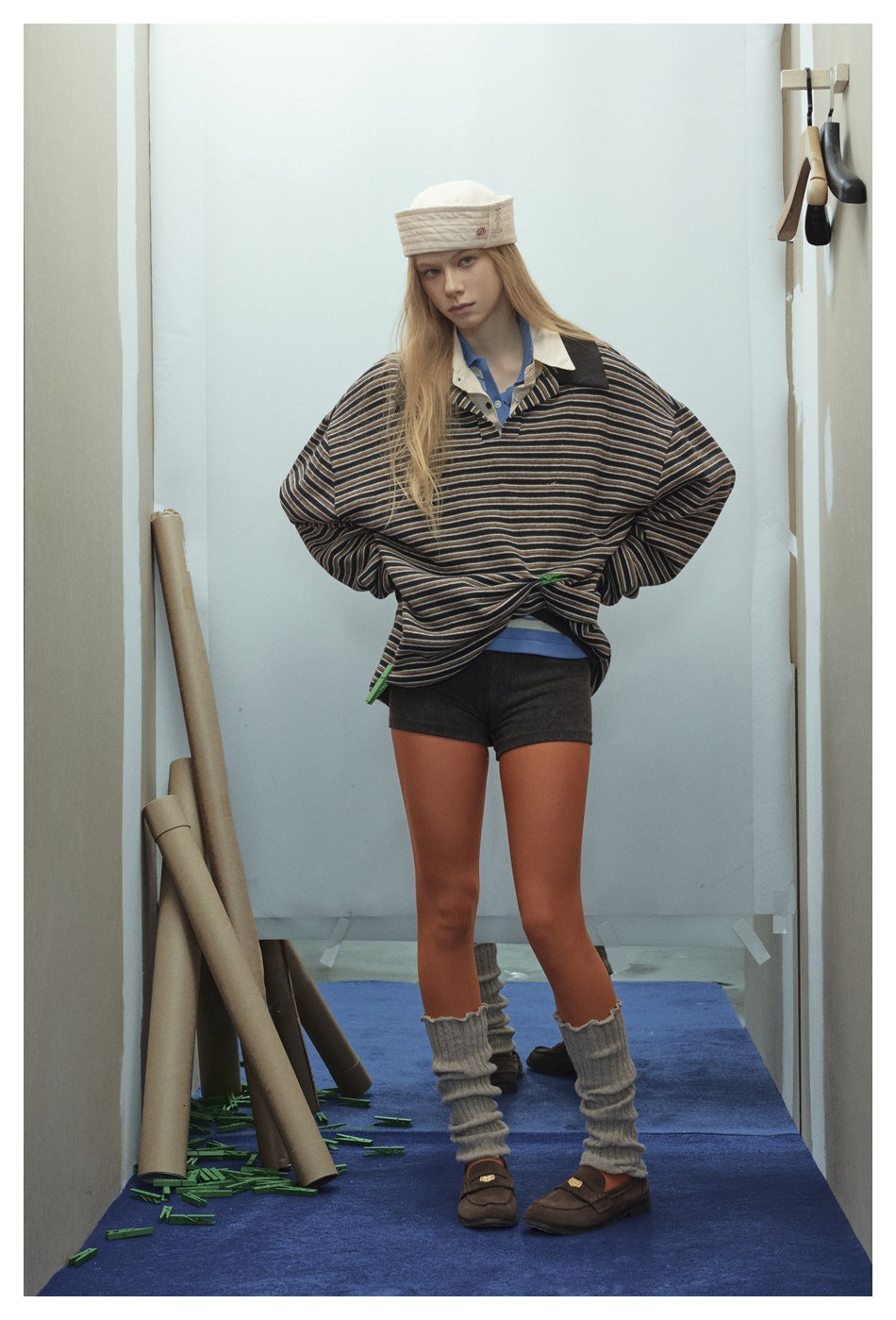 Model wearing an oversized black striped polo-collar pullover with shorts, orange tights and leg warmers