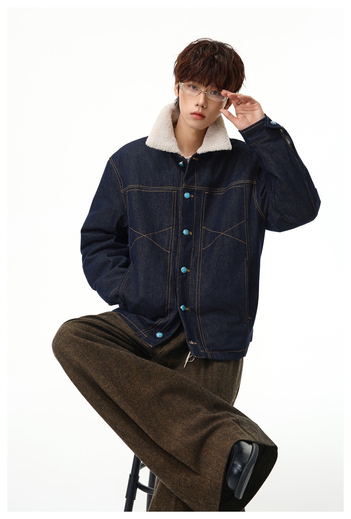 Model wearing a dark indigo denim jacket with a cream sherpa collar and turquoise buttons.