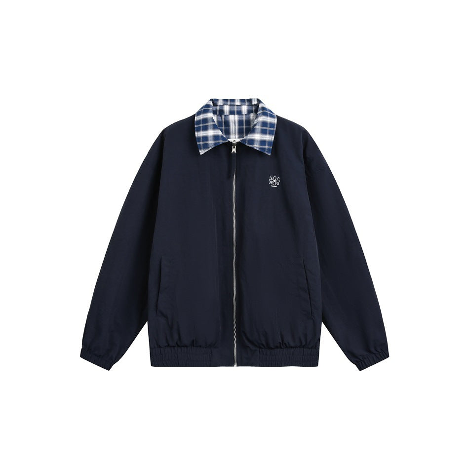 Front view of a navy zip jacket with a blue plaid collar, side pockets, elastic trim and a small white chest emblem.