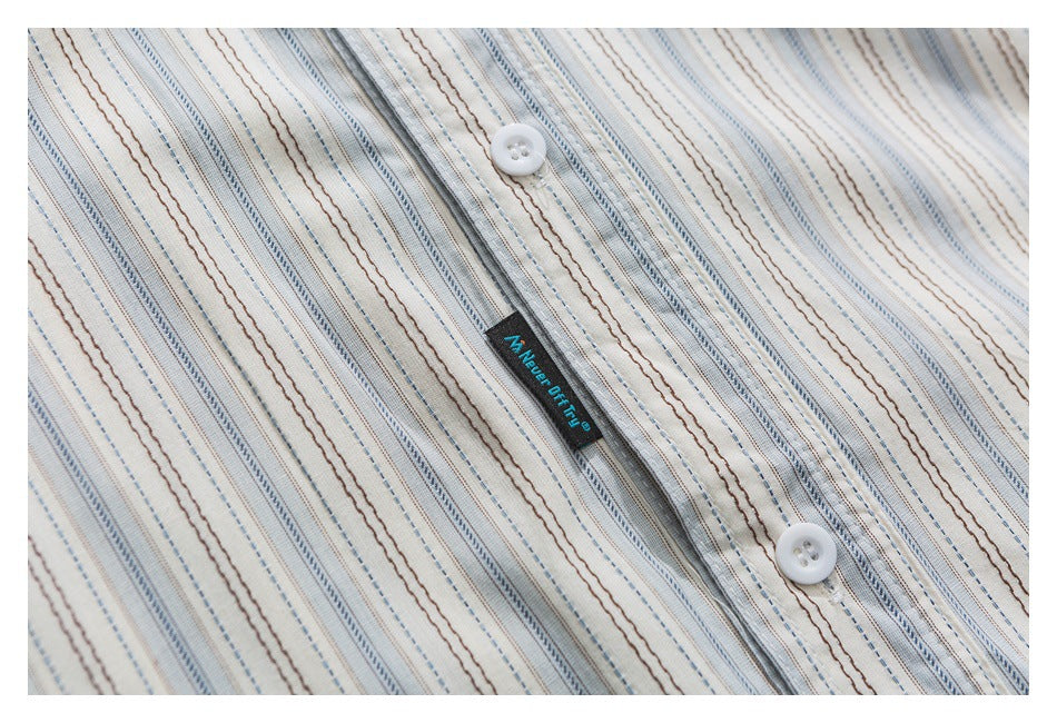 Close-up of white buttons and a black label on cream fabric with blue and brown stripes.