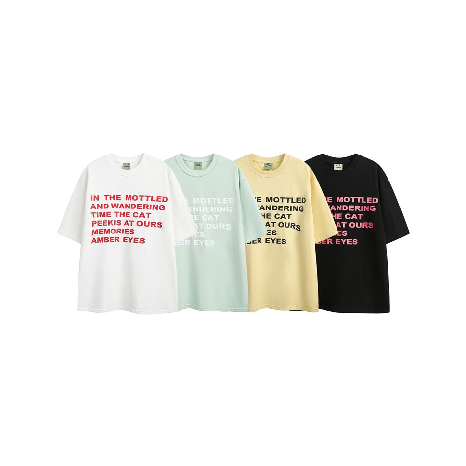 Four oversized short-sleeve crew-neck T-shirts in white, pale mint, pale yellow, and black, each with English text across the