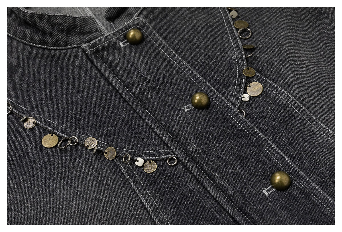 Close-up of the jacket's charcoal denim front, brass-tone buttons, and mixed metal charms along curved seams.