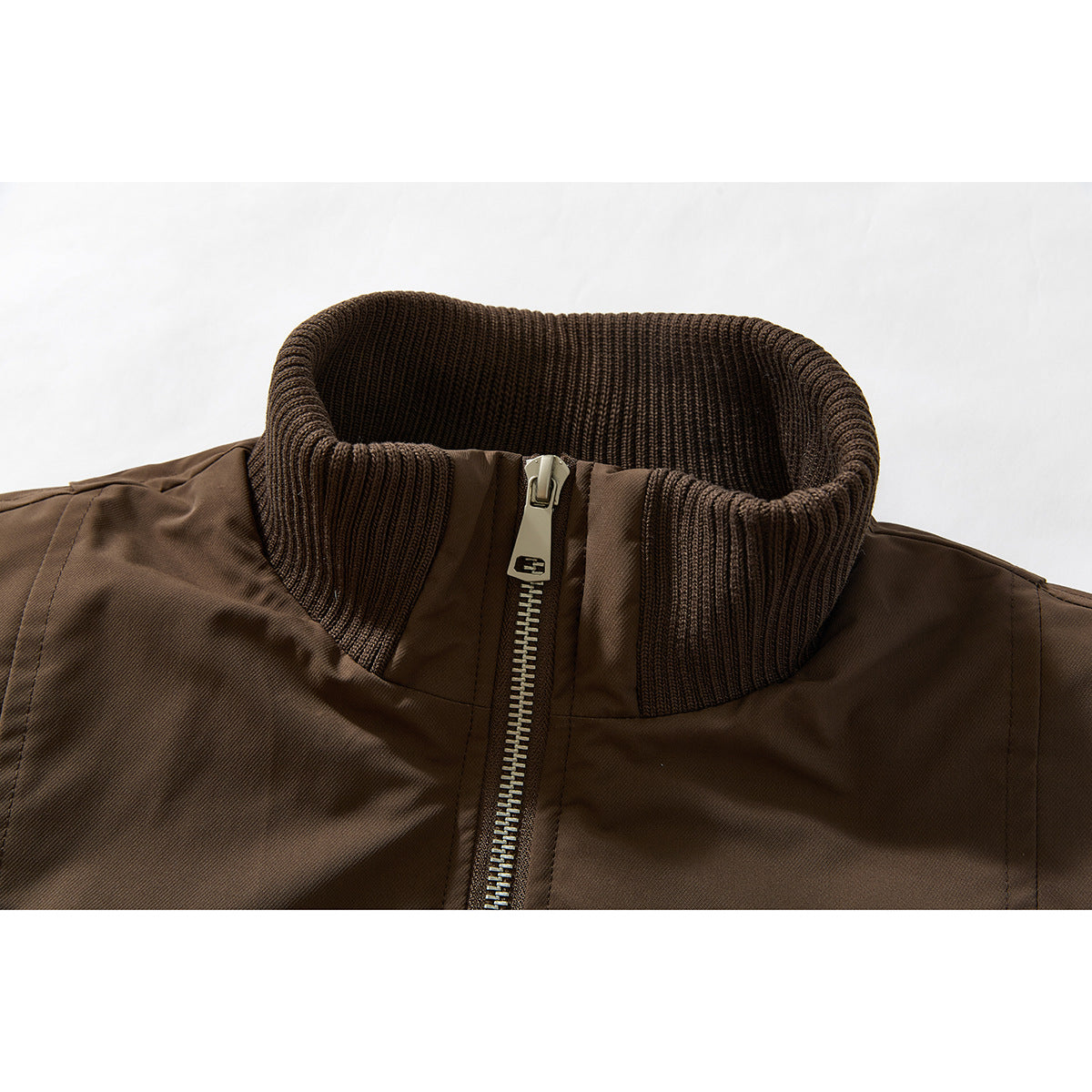 Close-up of a brown jacket's ribbed stand collar and metal front zipper.