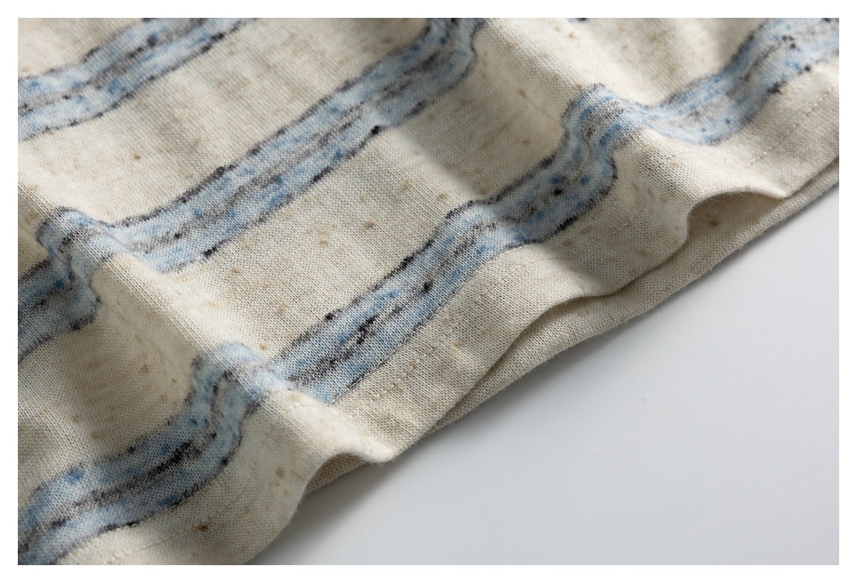 Close-up of cream striped fabric gathered into folds, showing a stitched edge.