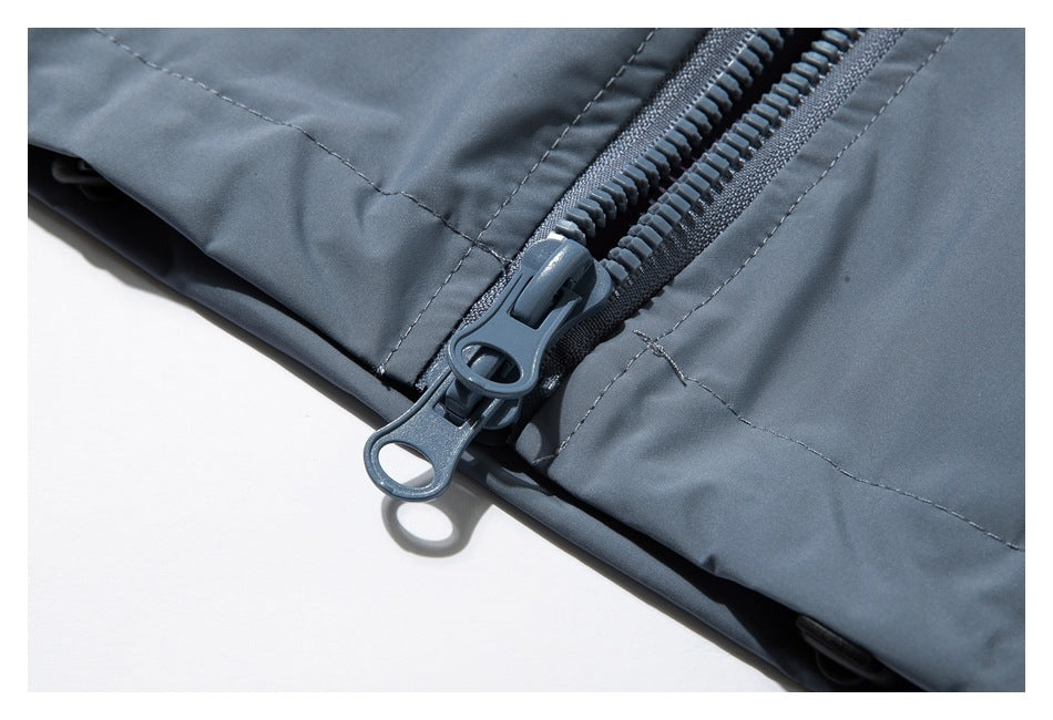 Close-up of a gray-blue zipper pull and reinforced stitching on a garment.