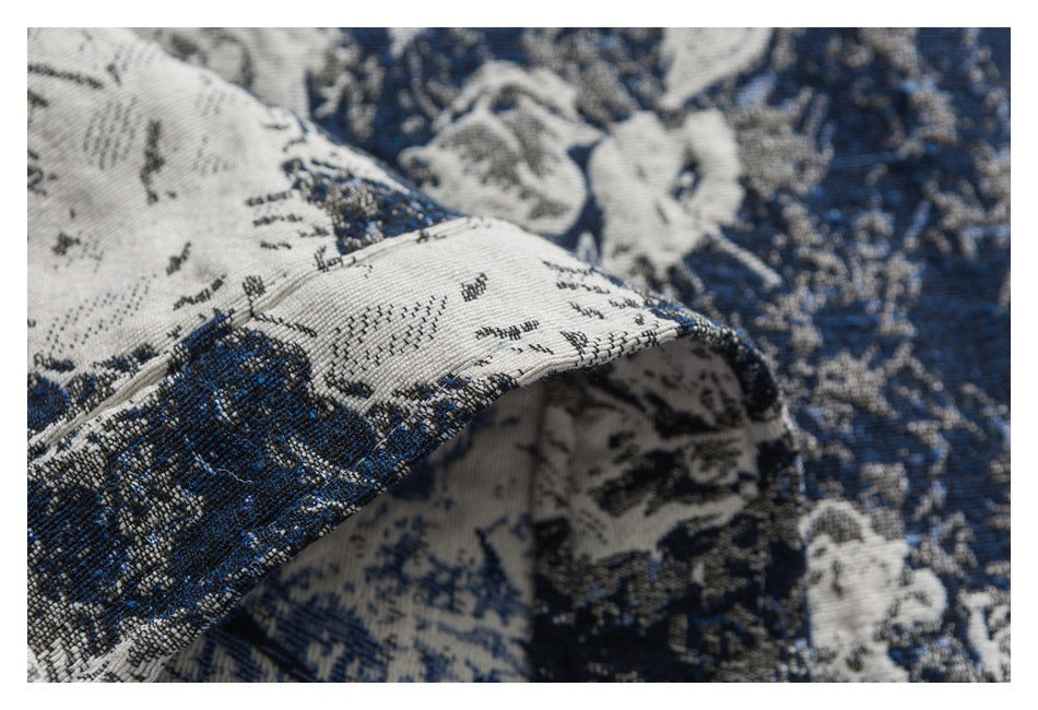 Close-up of a folded, stitched edge on blue and ivory floral-patterned fabric.