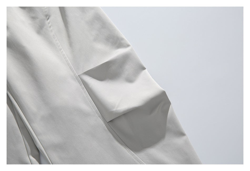 Close-up of light gray trouser leg showing a stitched seam and folded knee detail.