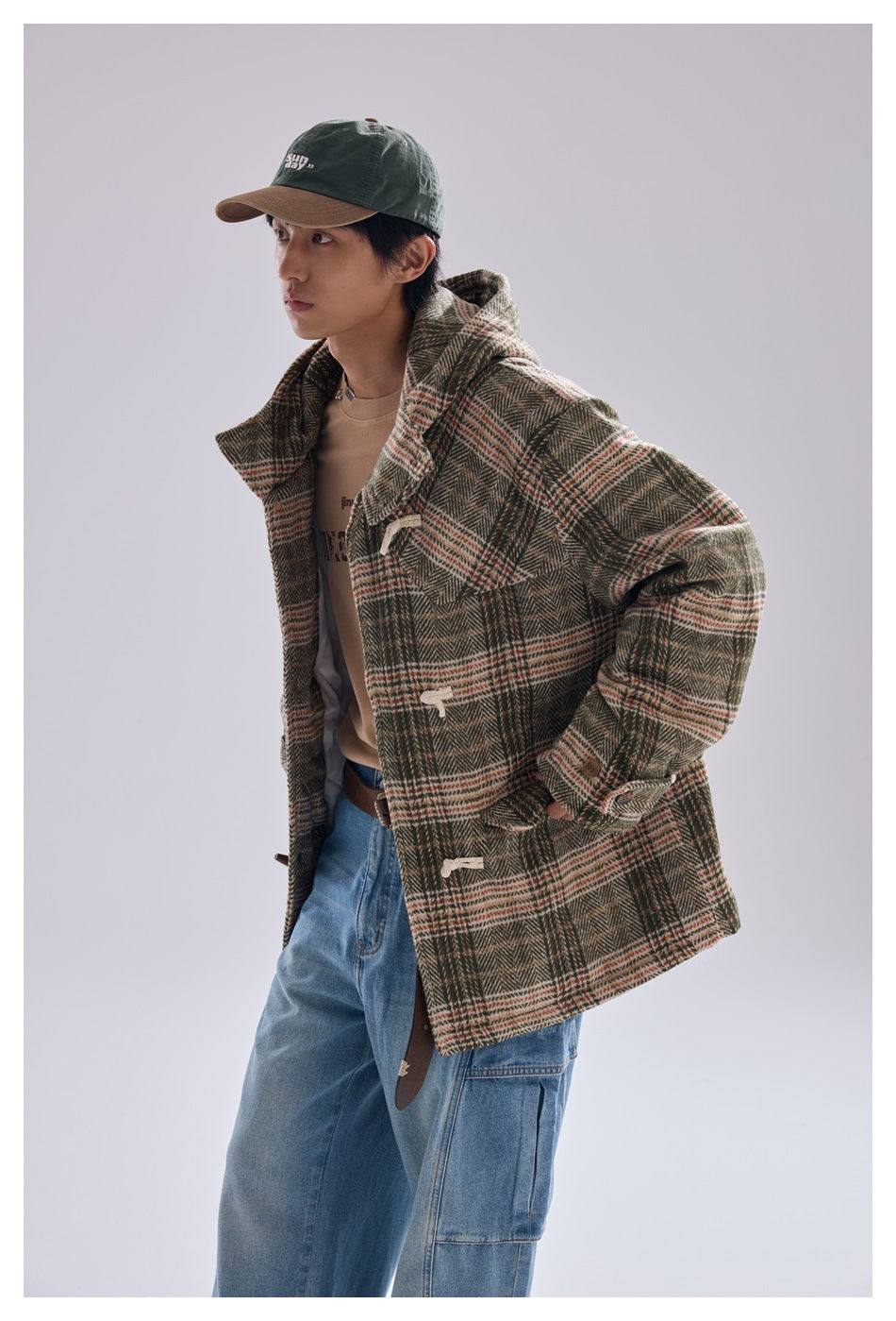 Model wearing green plaid hooded toggle jacket open over a tan top with light blue jeans, side view