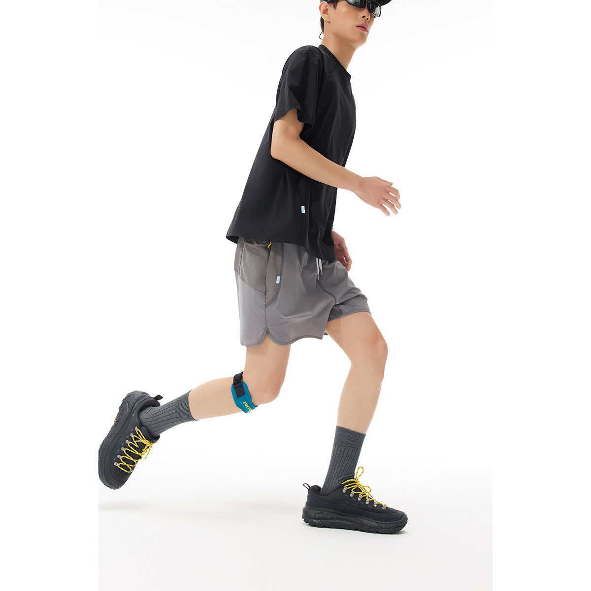 Model running in gray drawstring shorts and a black shirt, shown in profile against a white background.