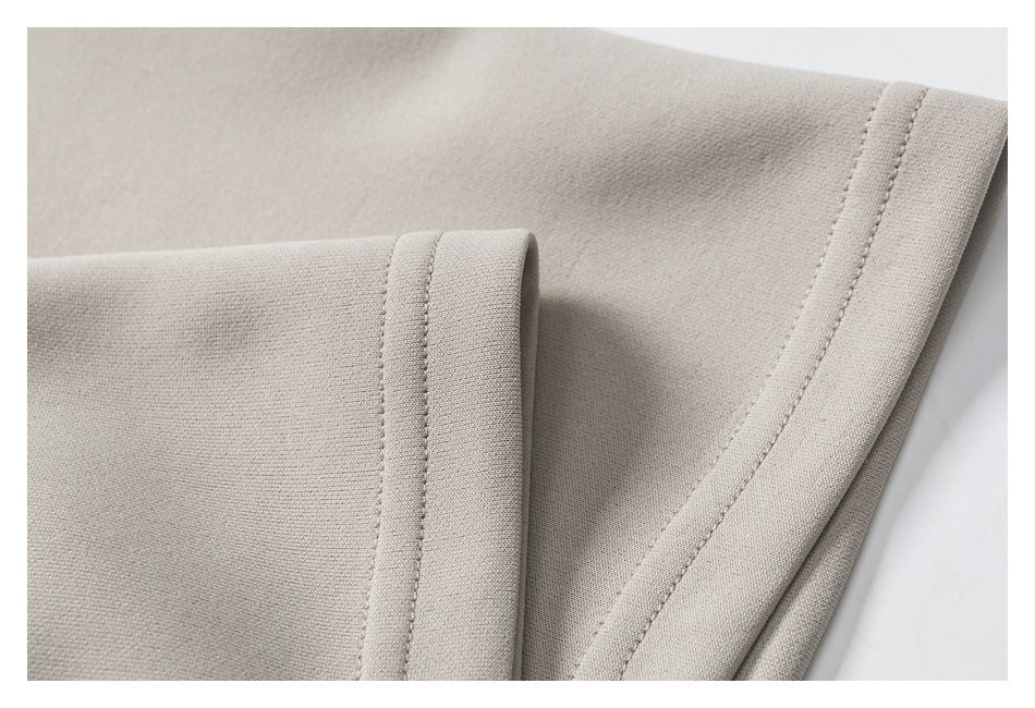 Close-up of light beige garment panels with neatly stitched folded edges.