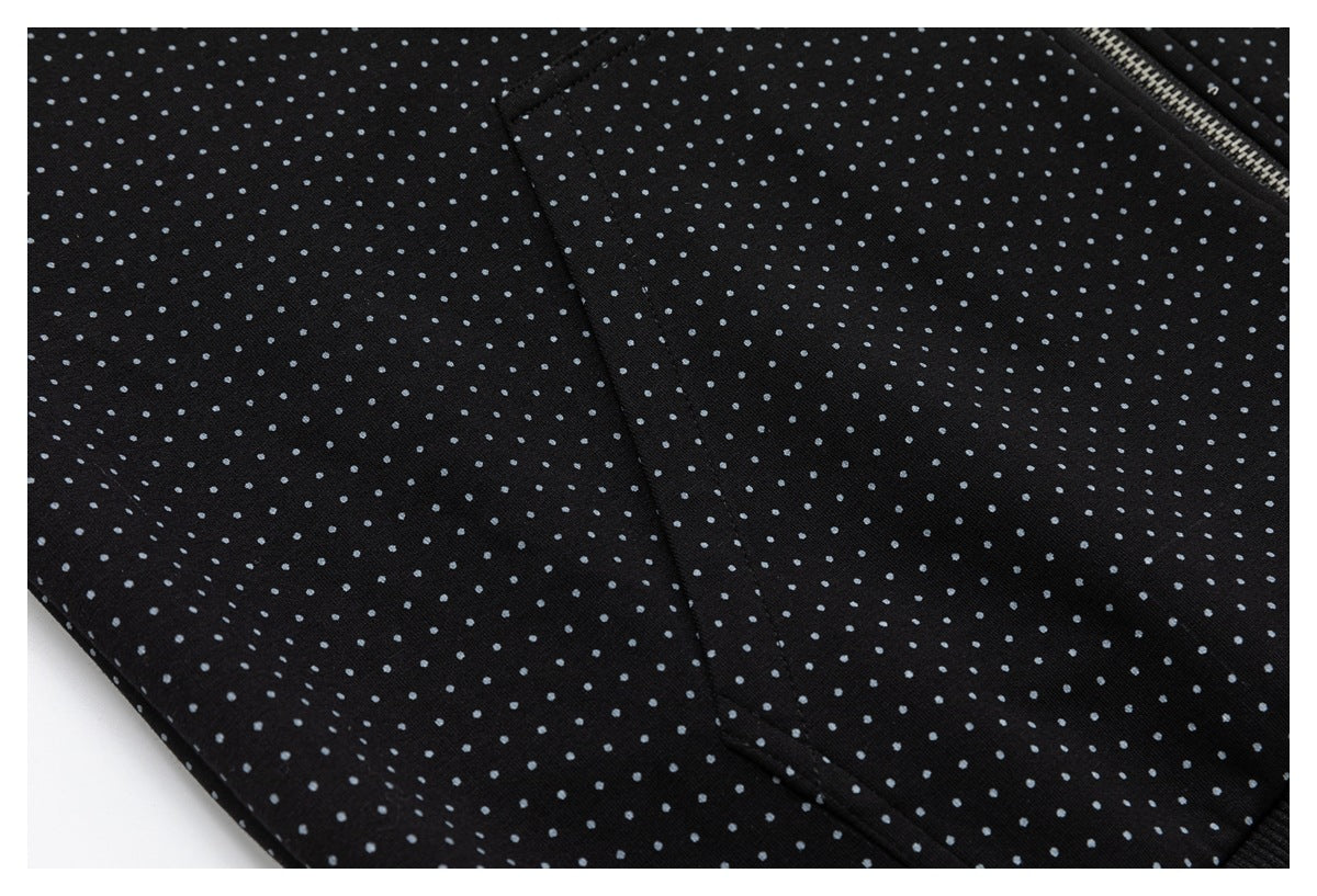 Close-up of a pocket seam on black fabric patterned with small gray dots.