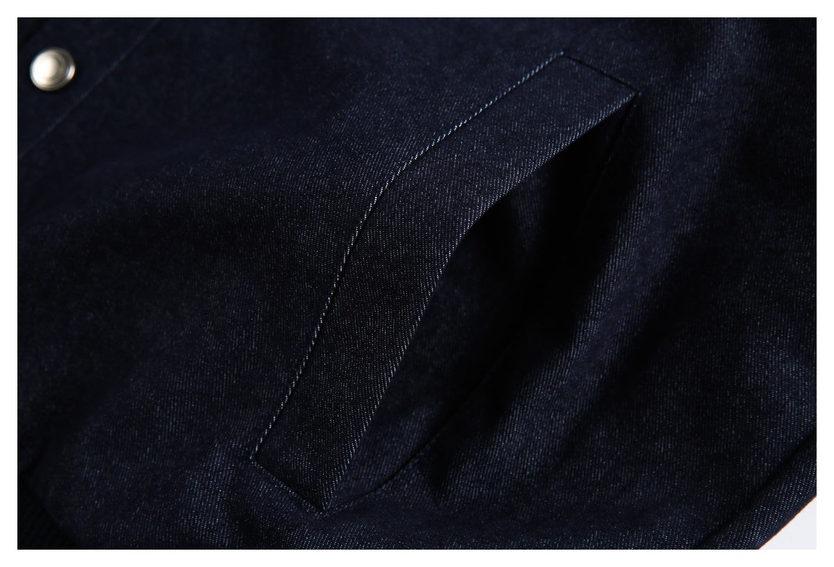 Close-up of a slanted welt pocket on dark navy fabric, with a silver snap nearby.