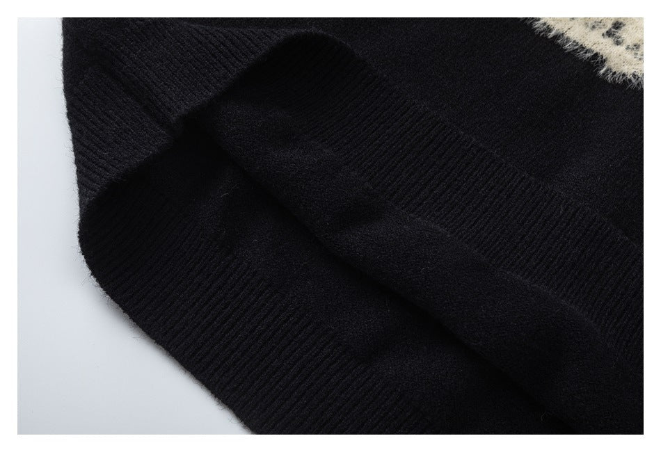 Close-up of black ribbed knit edges and folded fabric, with a small cream-colored patterned area at the upper right.