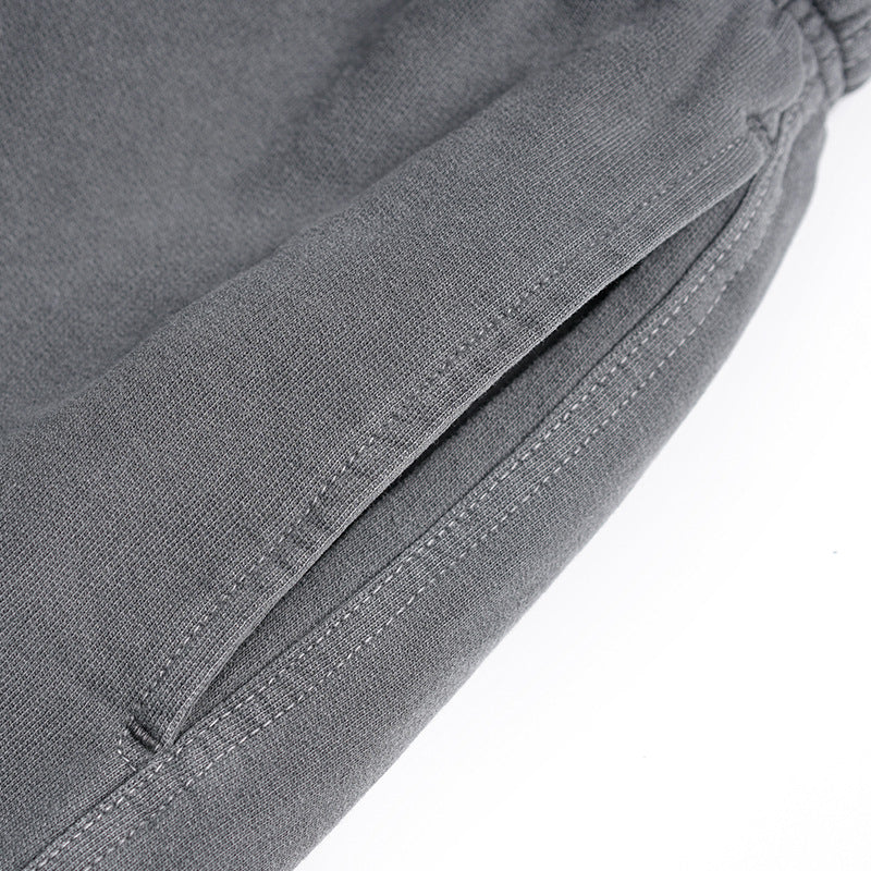 Close-up of a stitched side pocket on gray shorts.