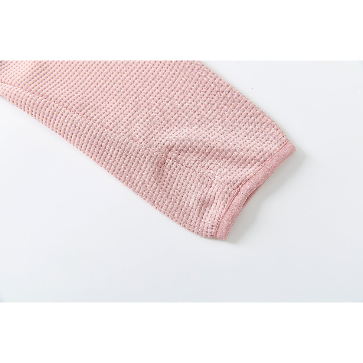 Close-up of a pink jacket sleeve and its textured fabric and finished cuff.