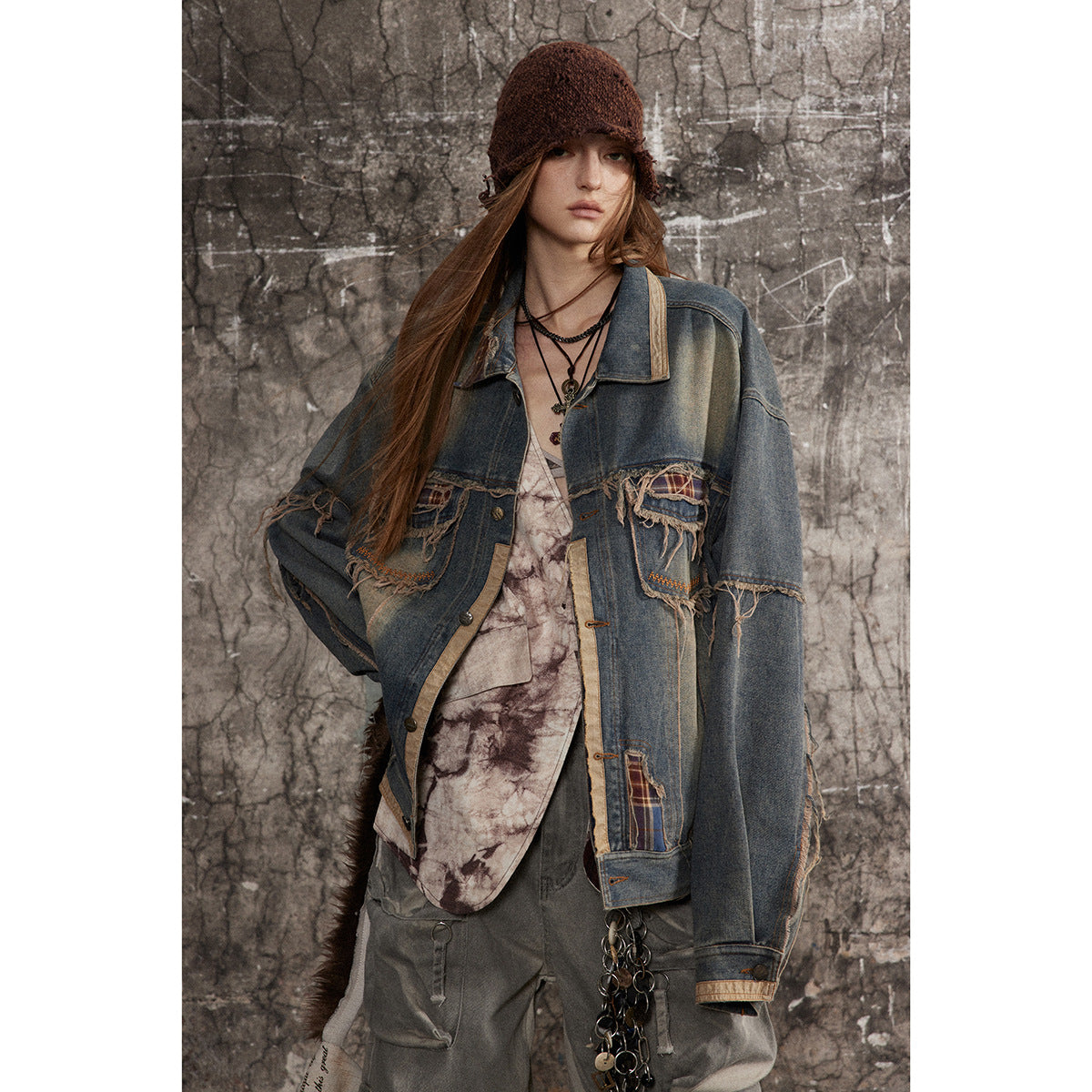 Model wearing an oversized blue denim jacket with frayed plaid-trimmed pockets and patchwork details.