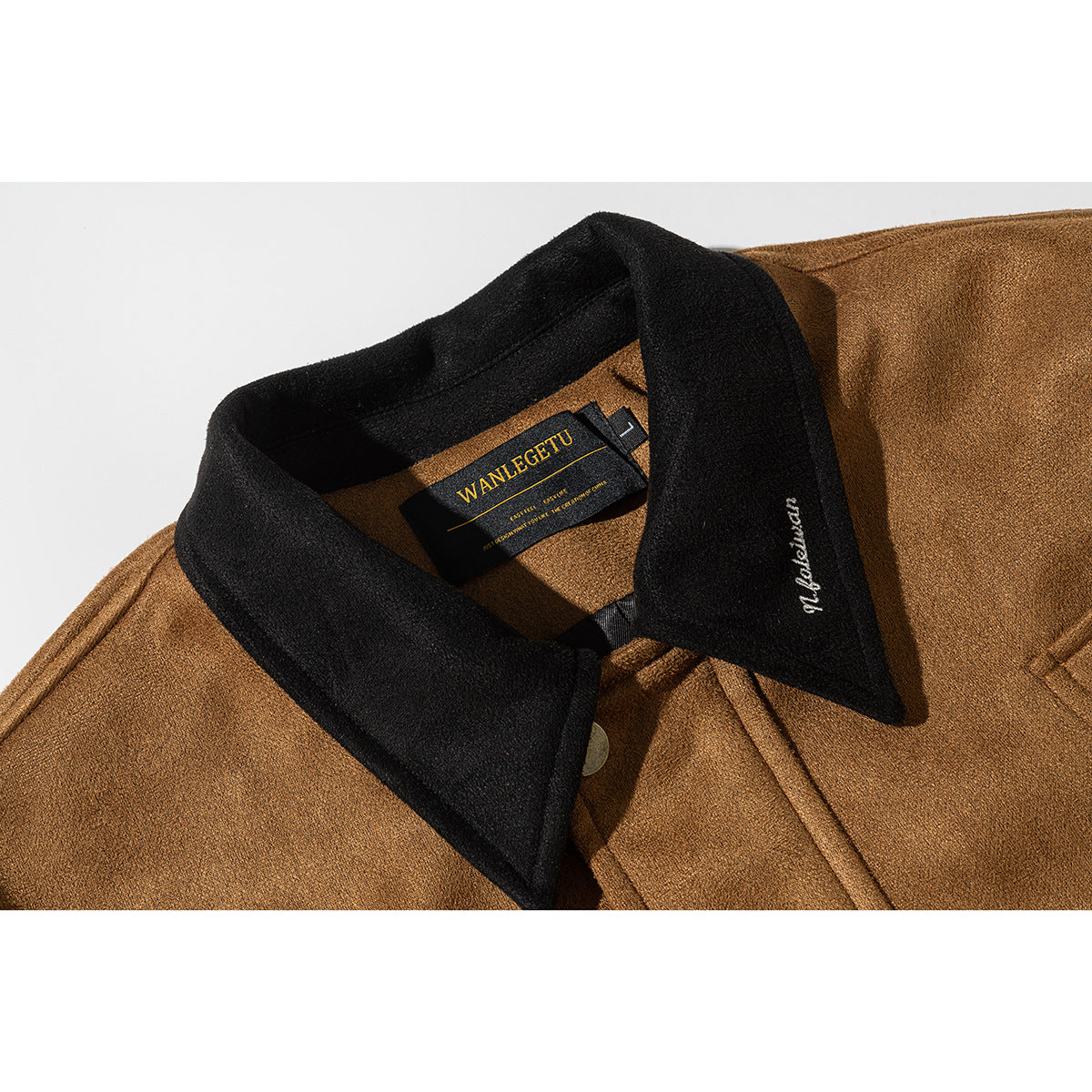 Close-up of a brown jacket with a black collar, showing the inner neck label and embroidered collar script.